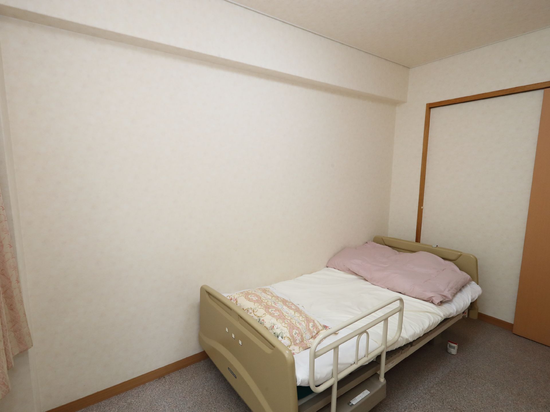 部屋の一角に置かれた白いマットレスの敷いてあるベッド