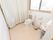大きなカーテンで仕切られたトイレの個室。肘掛けの取り付けられた洋式便器と、洗面台が１つずつ備え付けられている。
