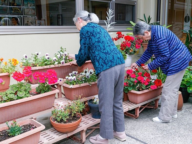たくさんのプランターがホームの周りに設置され、熱心に花の世話をしている高齢者たち。