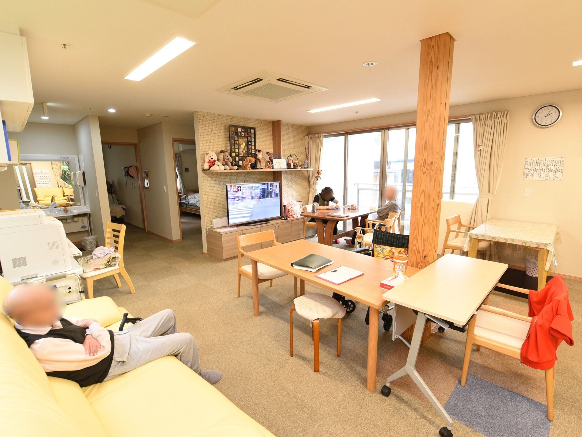広々とした明るいリビングである。床にパネルカーペットが敷かれており、ソファや椅子がセットされたテーブルが置かれている。