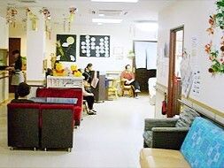 ダークグレーの2階建ての建物。玄関先には大きな車寄せが付き、外壁にはホームのマークが貼られている。
