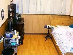 車いすの高齢女性と紺のポロシャツを着た女性スタッフが寄り添い微笑んでいる。
