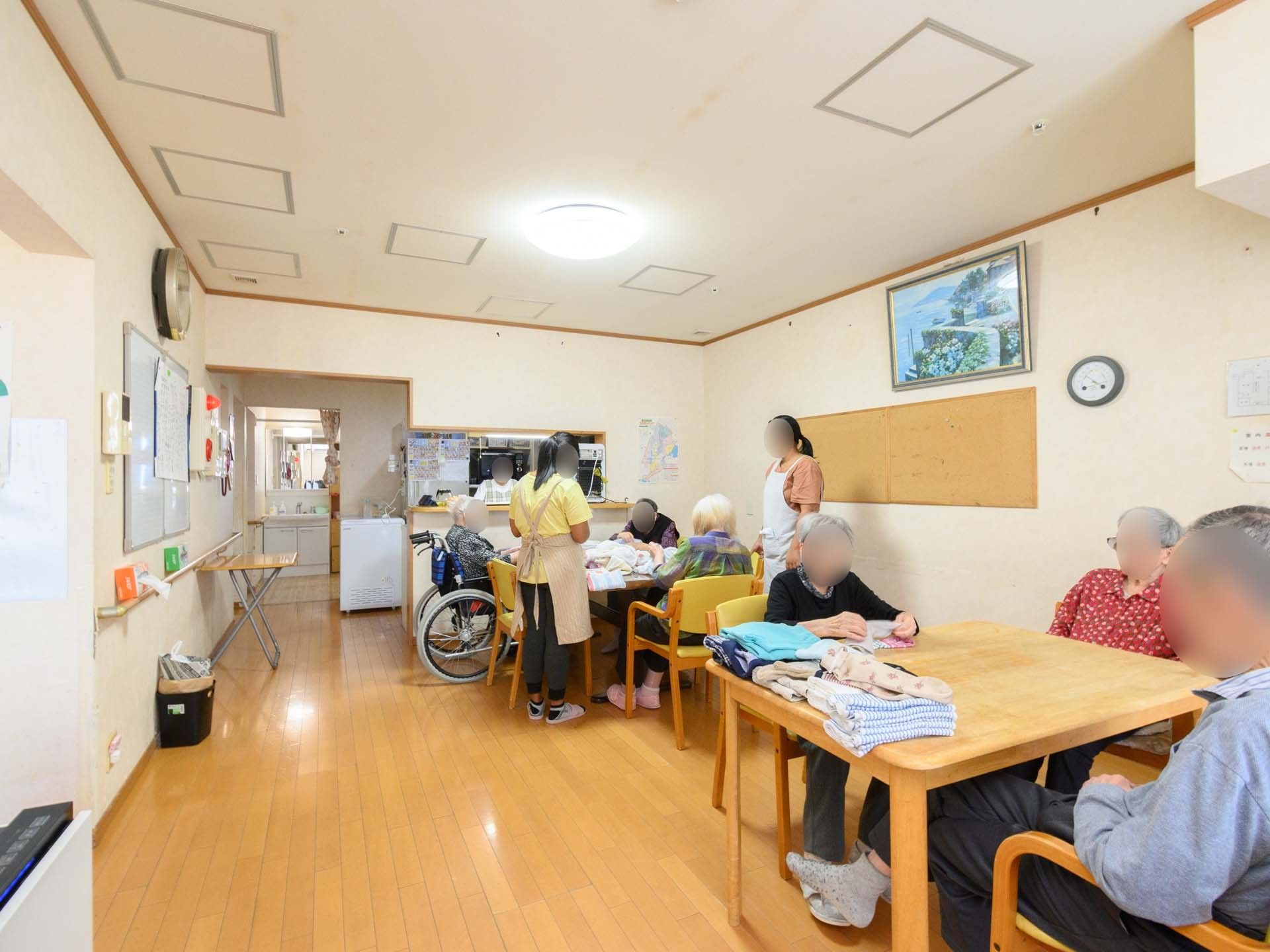 白いポロシャツを着た男性スタッフと高齢女性がカルテのようなものを見ながら話している。