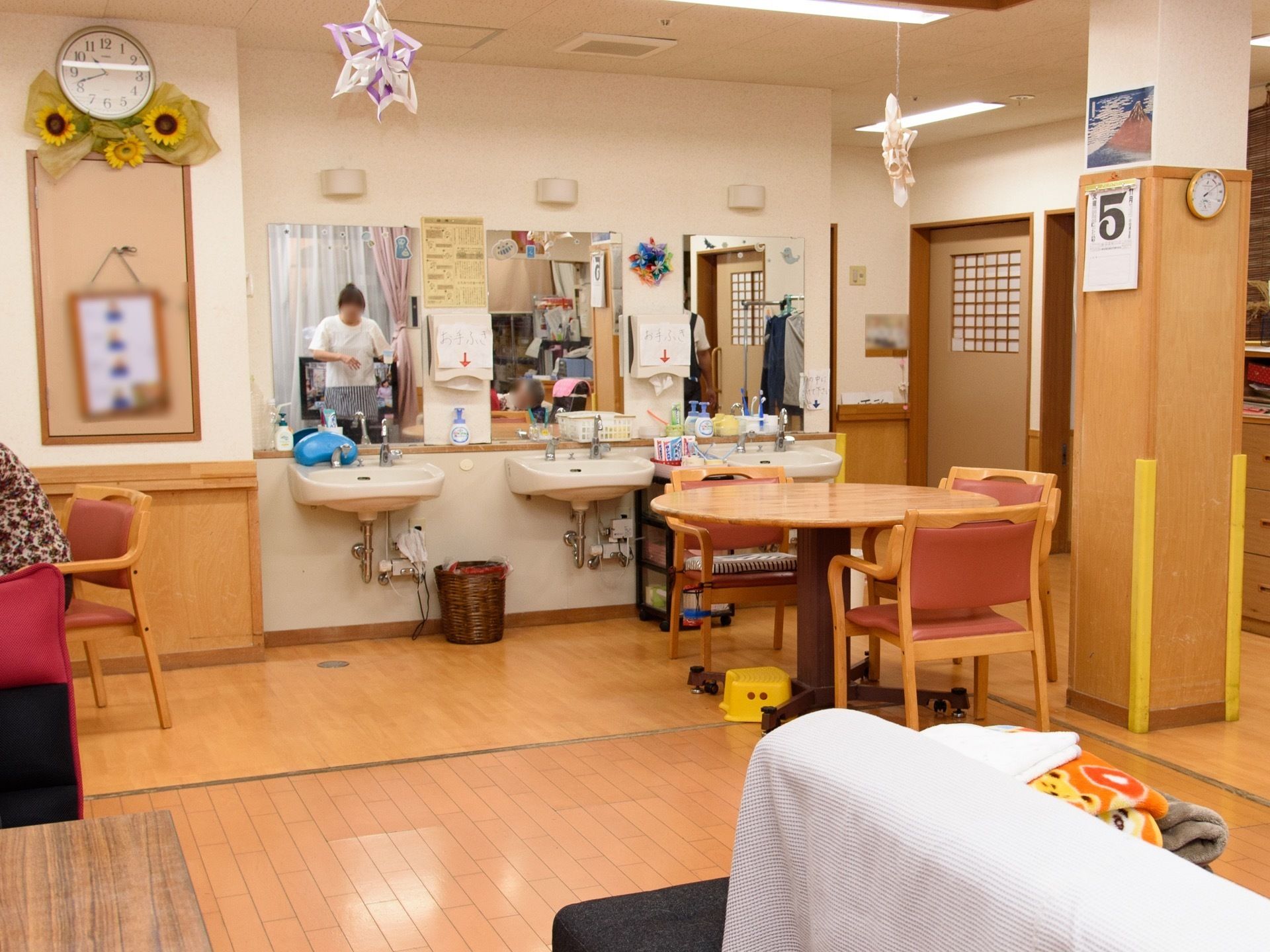 丸テーブルを囲むように椅子が３脚置いてある。柱の下は、四方にクッション材を取り付けて、角にぶつける危険性を軽減するようにしている。