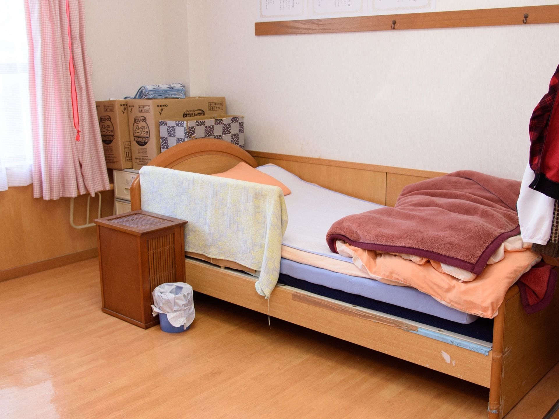 居室には転落防止柵が取り付けられたベッドが設置されている。窓があり、ピンク色のカーテンがかけられている。