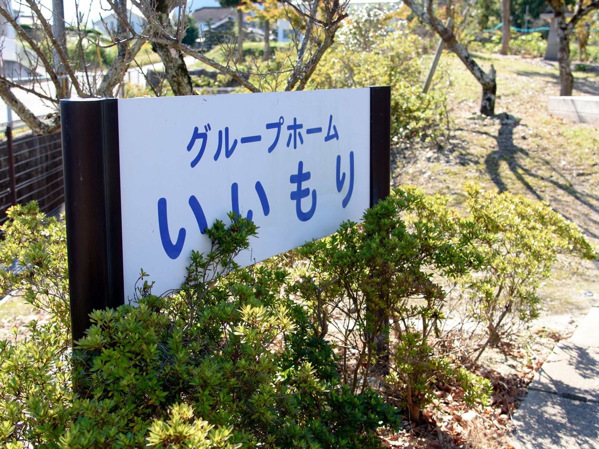 施設の敷地内に看板が設置されている。周りには木々が多く植えられており、自然に触れながら過ごすことができる。