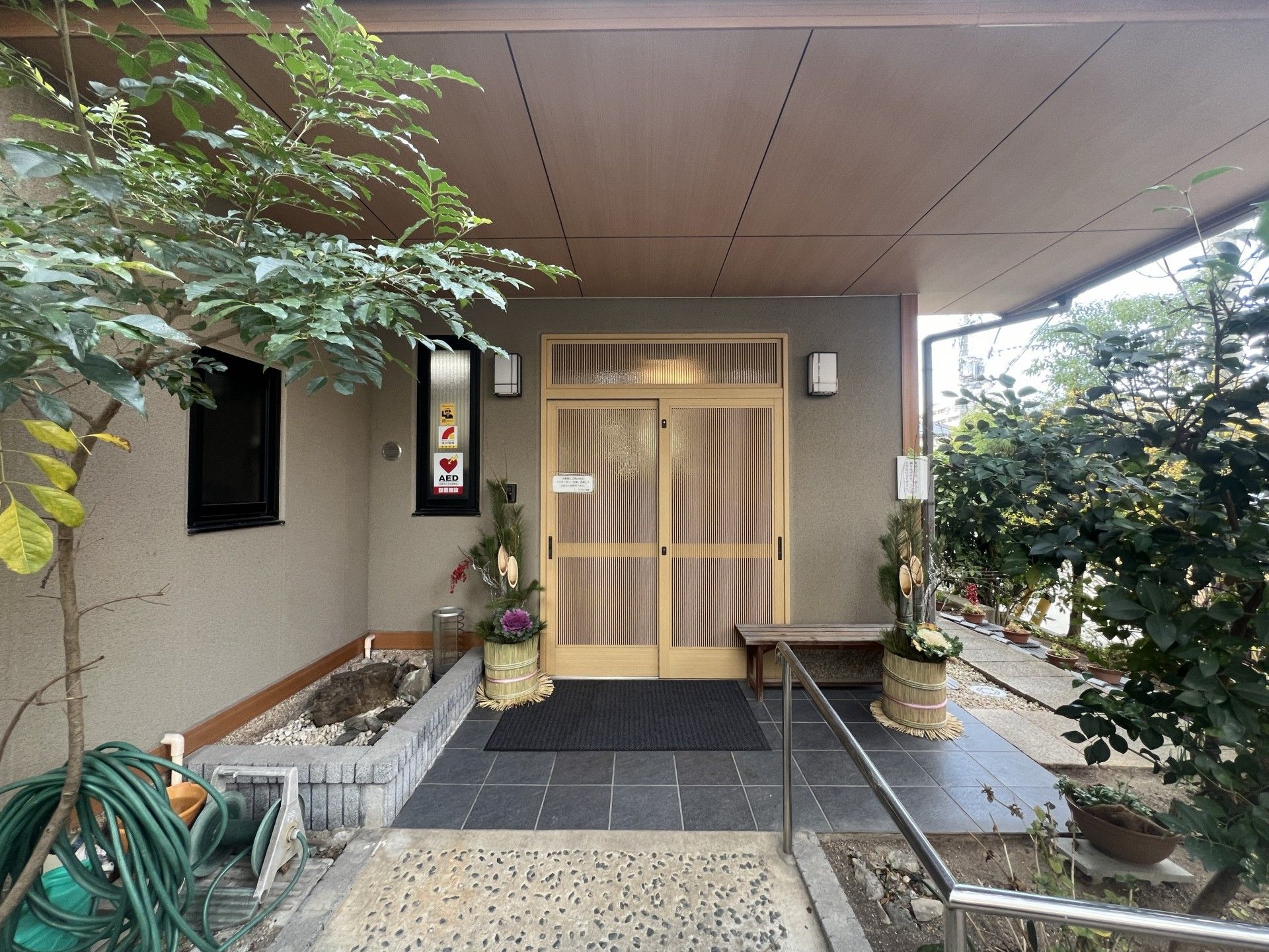 スタッフ３名とホームの名前が入った暖簾が伺える様子。