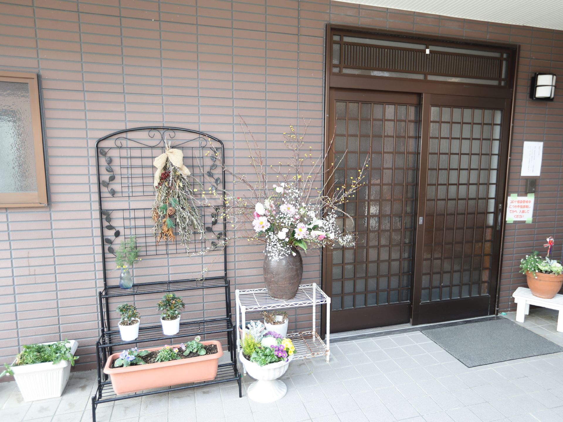 花の鉢植えが飾られた玄関前