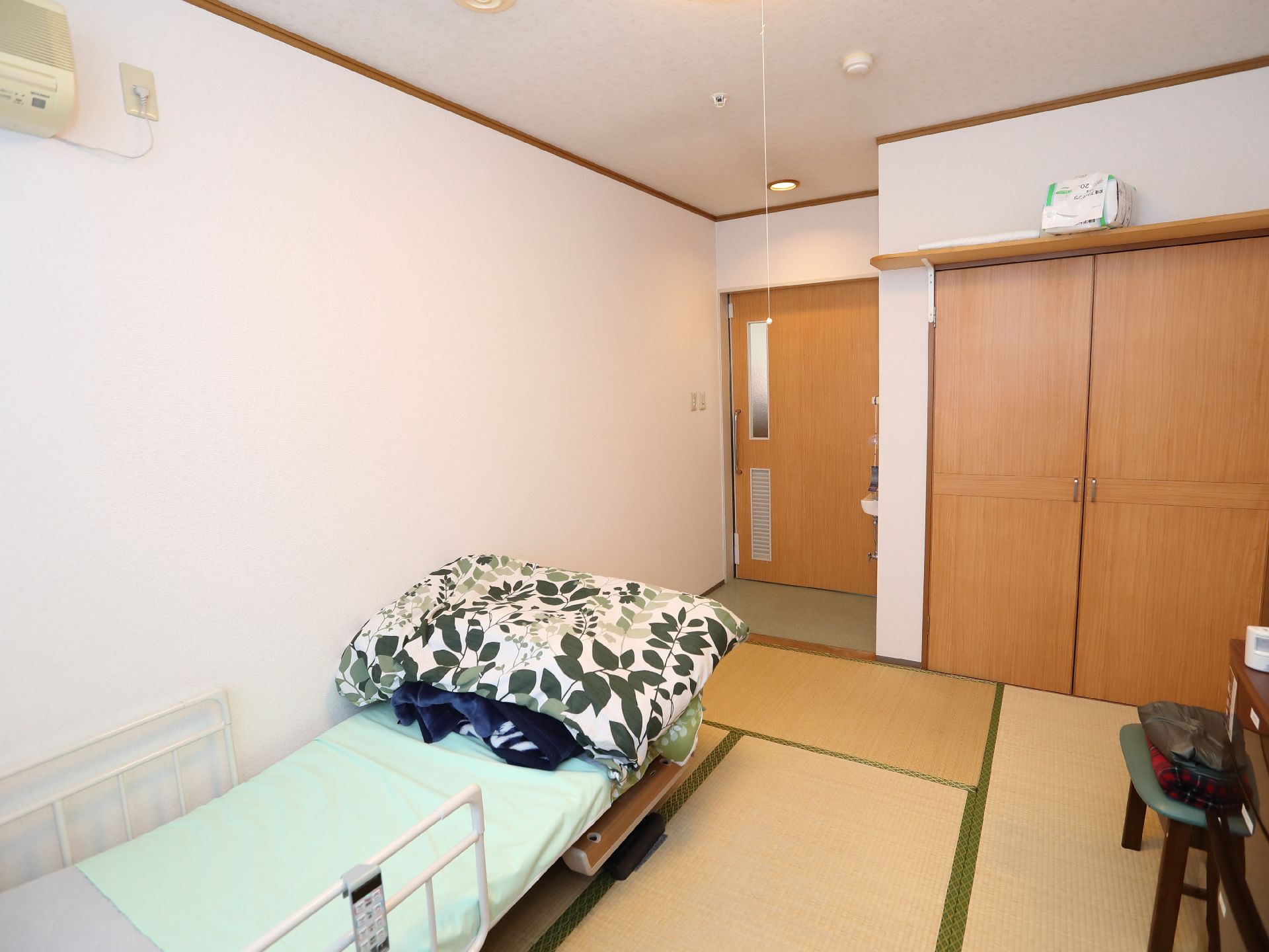 透明な浴槽は深く、お湯がたまっている。そばには椅子タイプのリフトが設置されている。