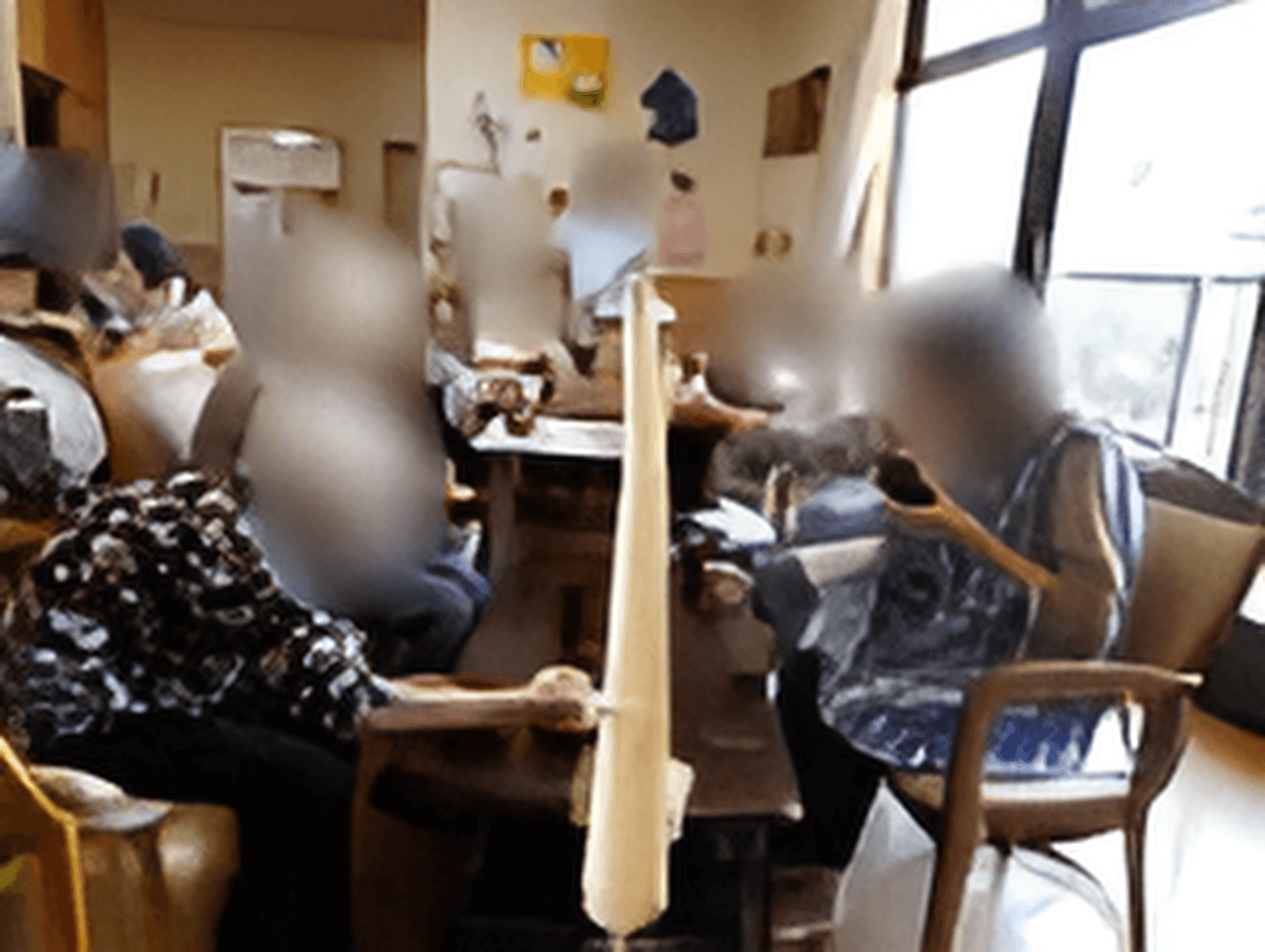 自然豊かな場所を車いすで散歩している高齢男性とそれを補助しながら話している女性スタッフ