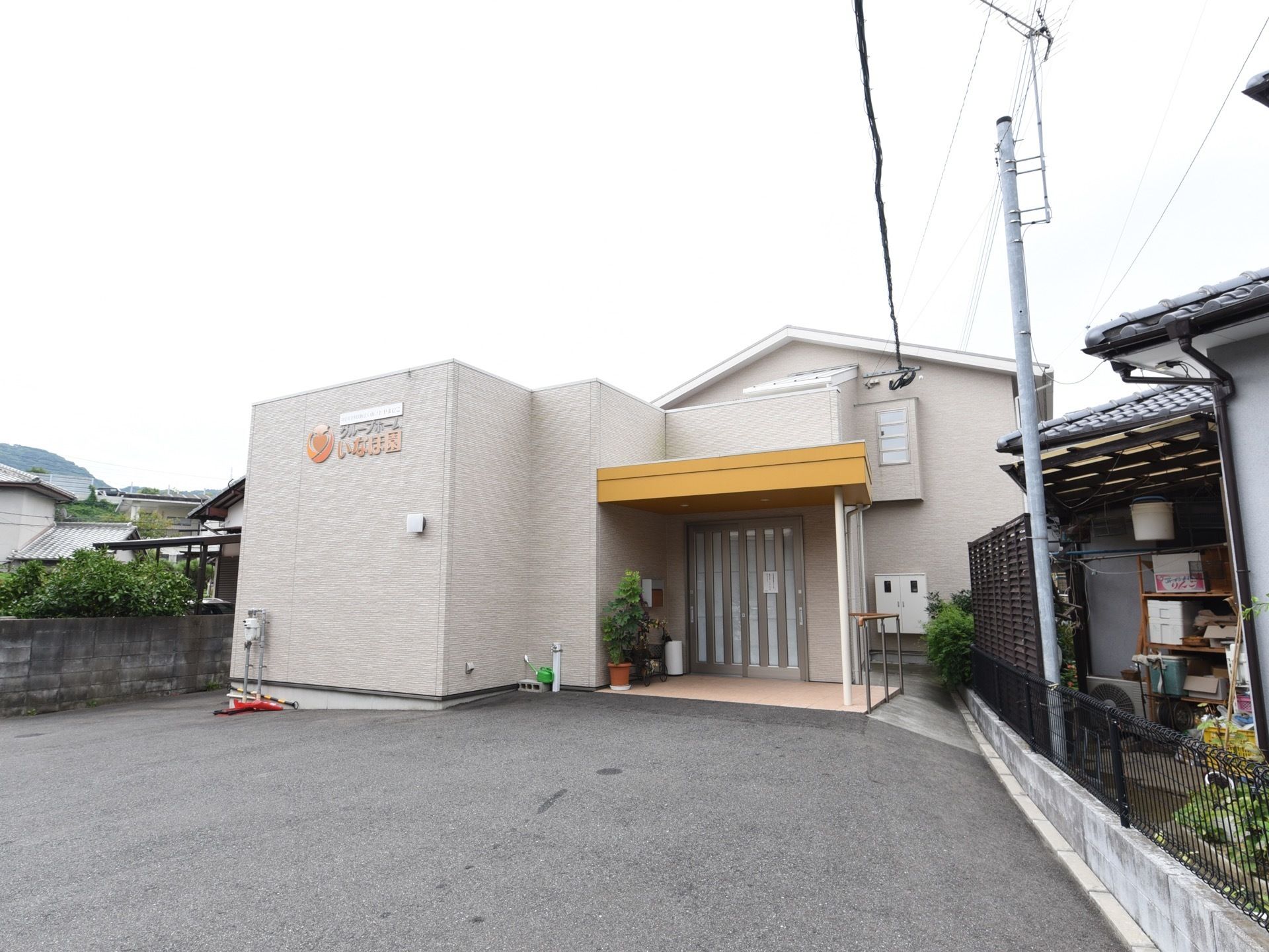施設は２階建ての建物である。エントランスには、黄色い屋根と手すりが設置されている。駐車スペースが建物前に設けられている。