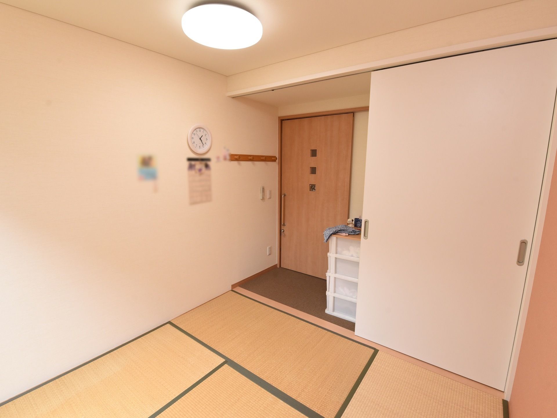 和室タイプの居室である。クローゼットが照明が完備されている。扉近くにチェストが置かれている。時計やハンガーフックが壁に取りつけられている。