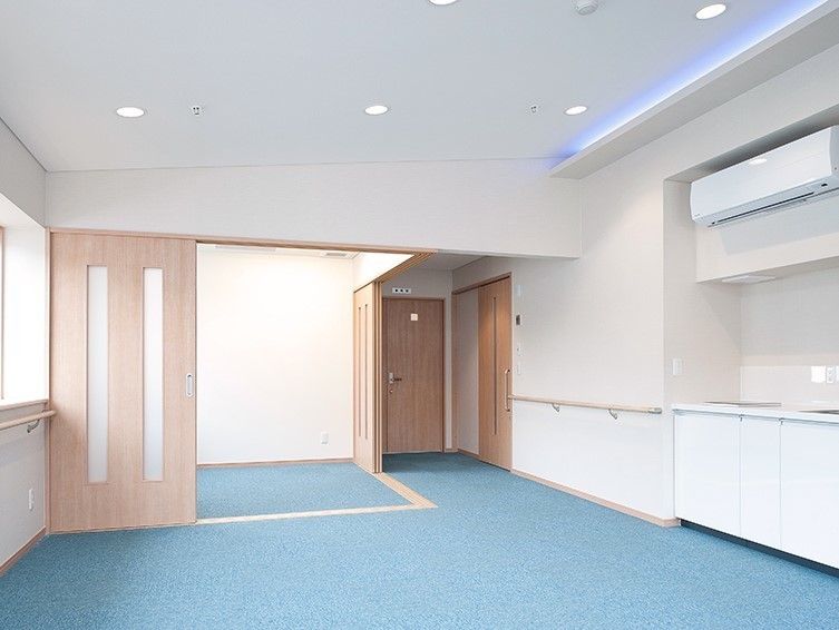 ひとりで部屋でくつろいでいる男性。ホワイトを基調とした部屋で明るい様子が分かる
