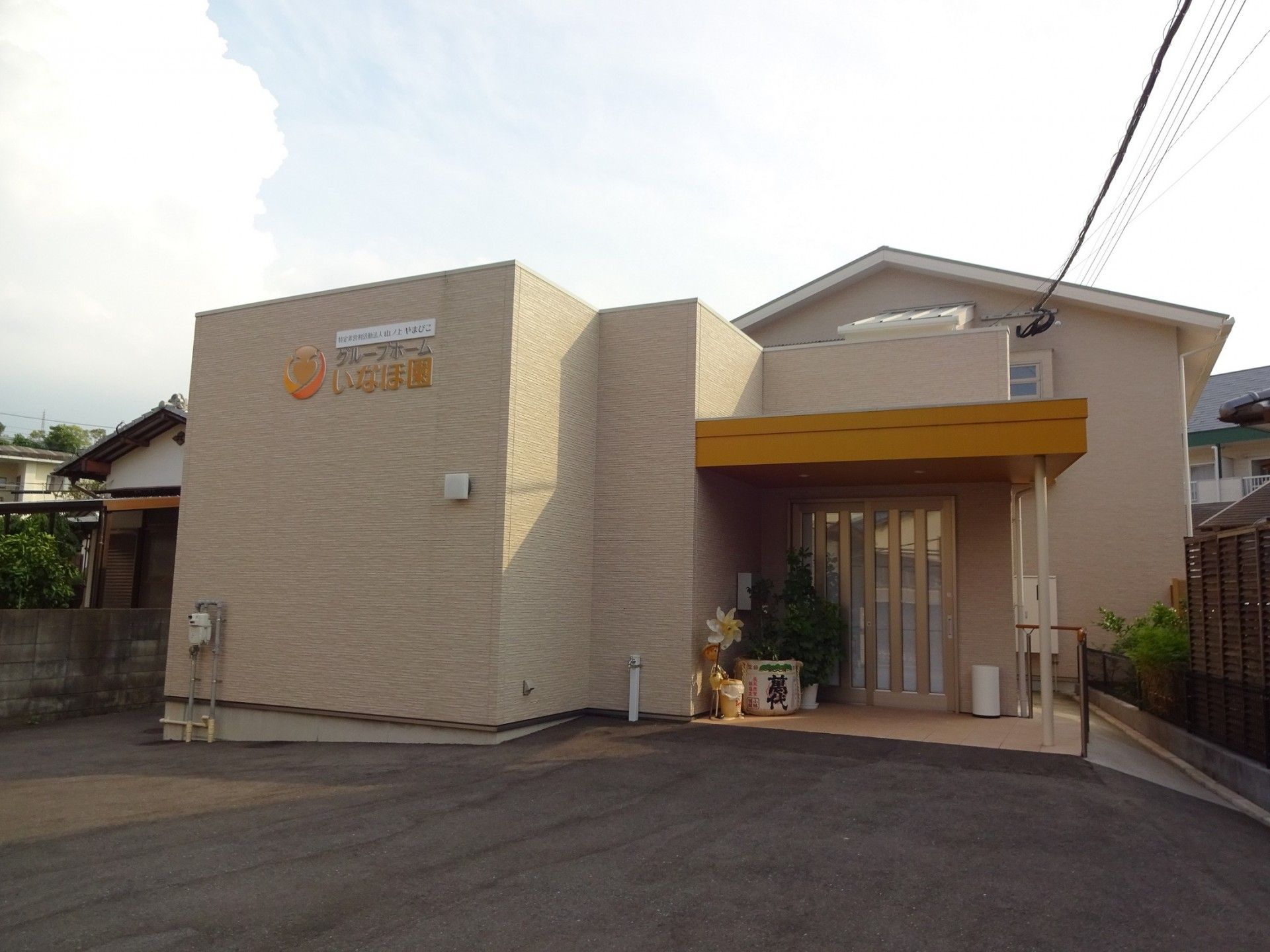 低層住宅の施設である。黄色とブラウンの外壁が印象的な裏口には、手すり付きの階段が設けられている。建物前の道路には、横断歩道がある。