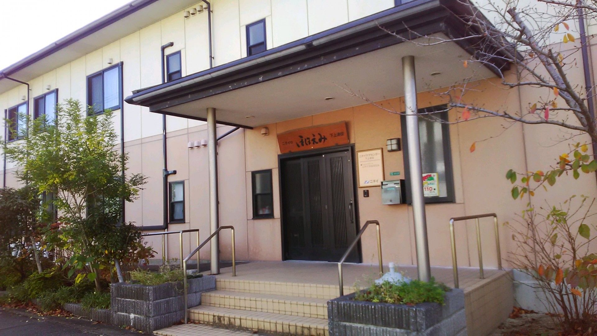 玄関に屋根がついている。入口には手すり付きの階段と手すり付きのスロープがある。