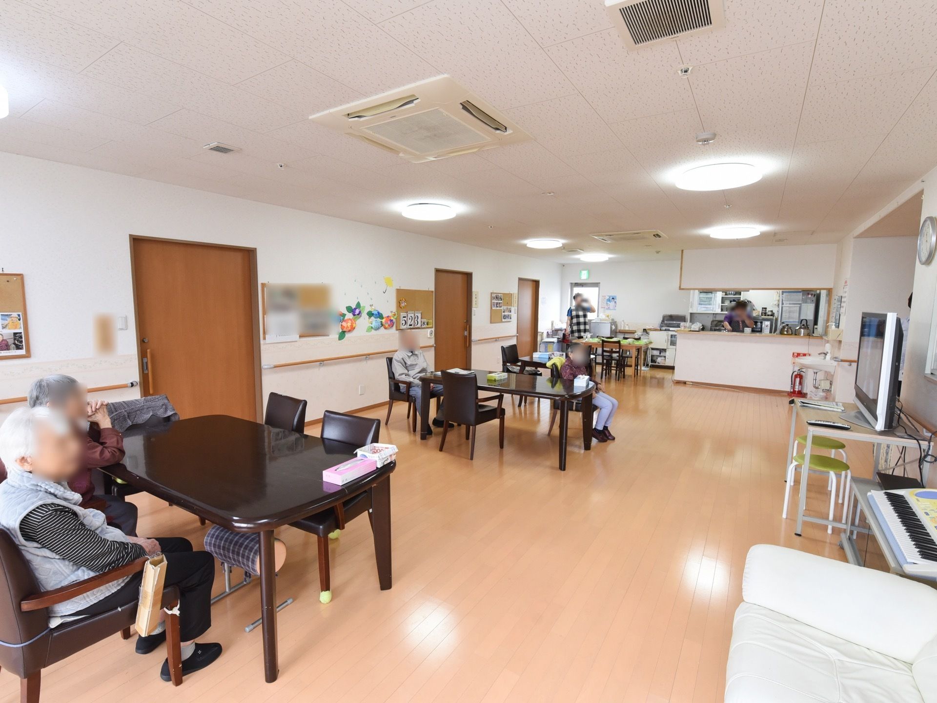 開放的なリビングダイニング。テレビが設置されており、隣には電子ピアノがある。テーブルの上にティッシュや小物入れが置かれている。