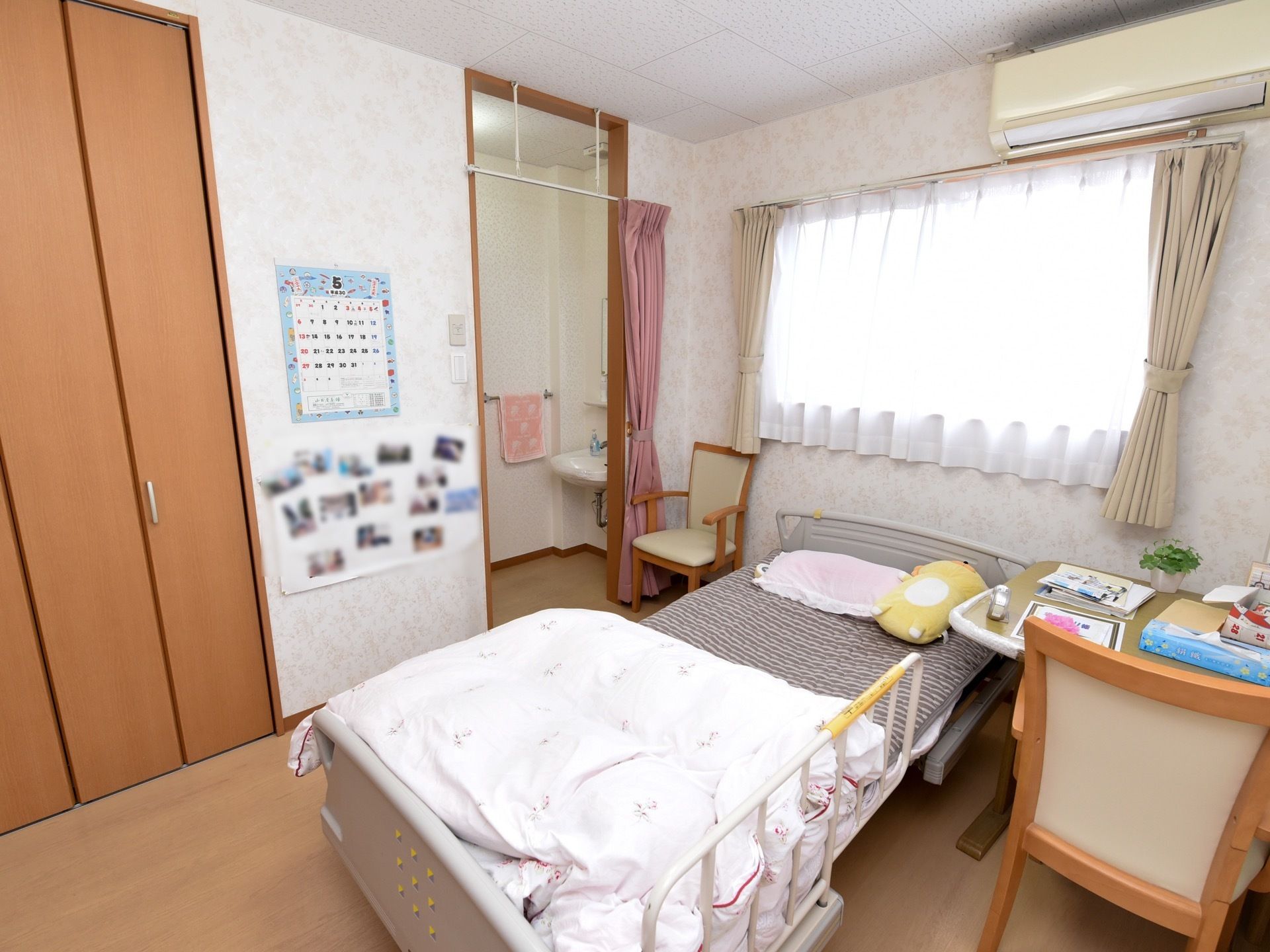 空調設備のついた居室。大きな収納が取り付けられており、奥には洗面スペースがある。ベッドにはベッドガードがついている。