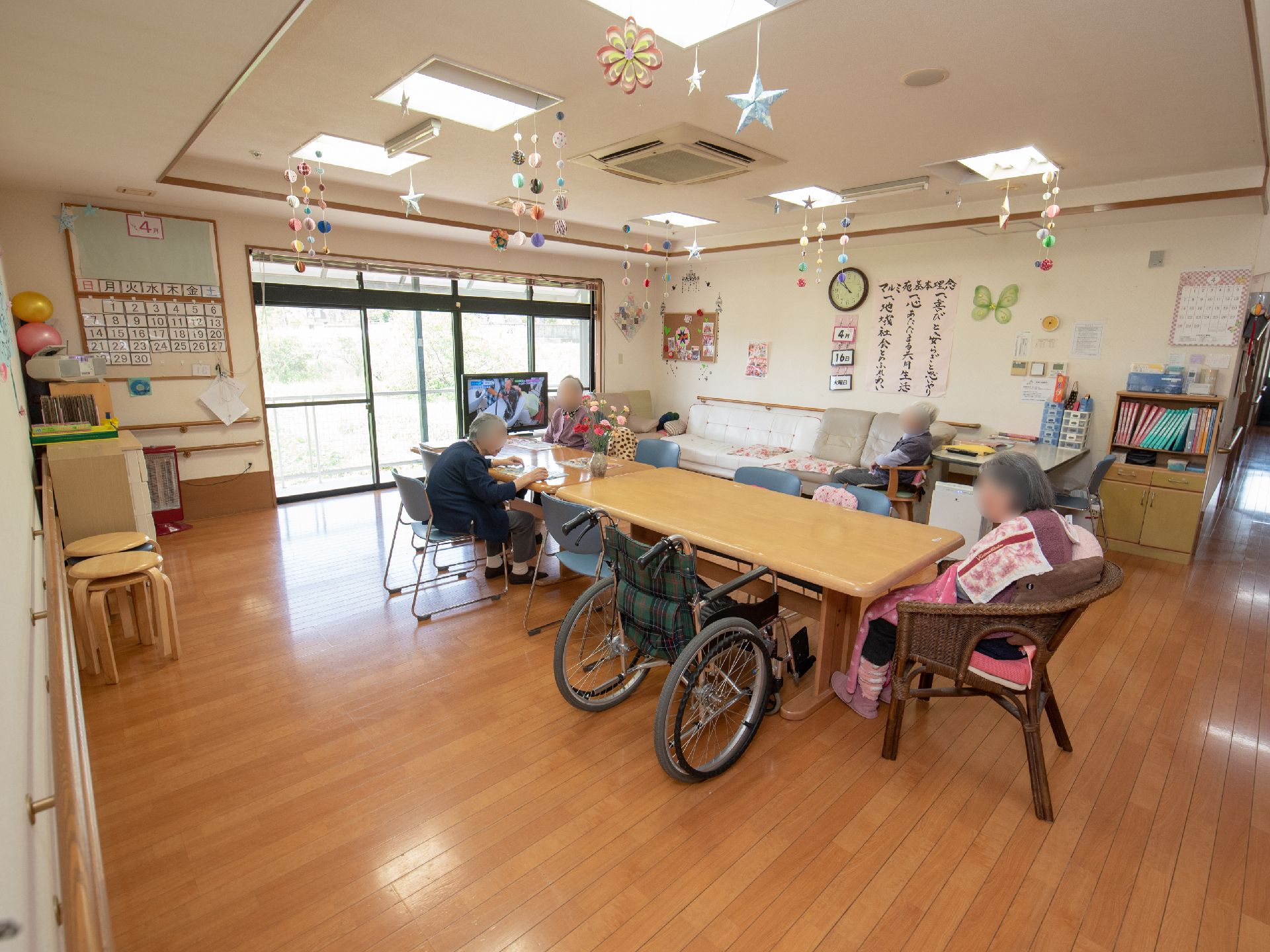 天井から色とりどりの紙飾りが吊るされているリビングで自由に過ごす入居者