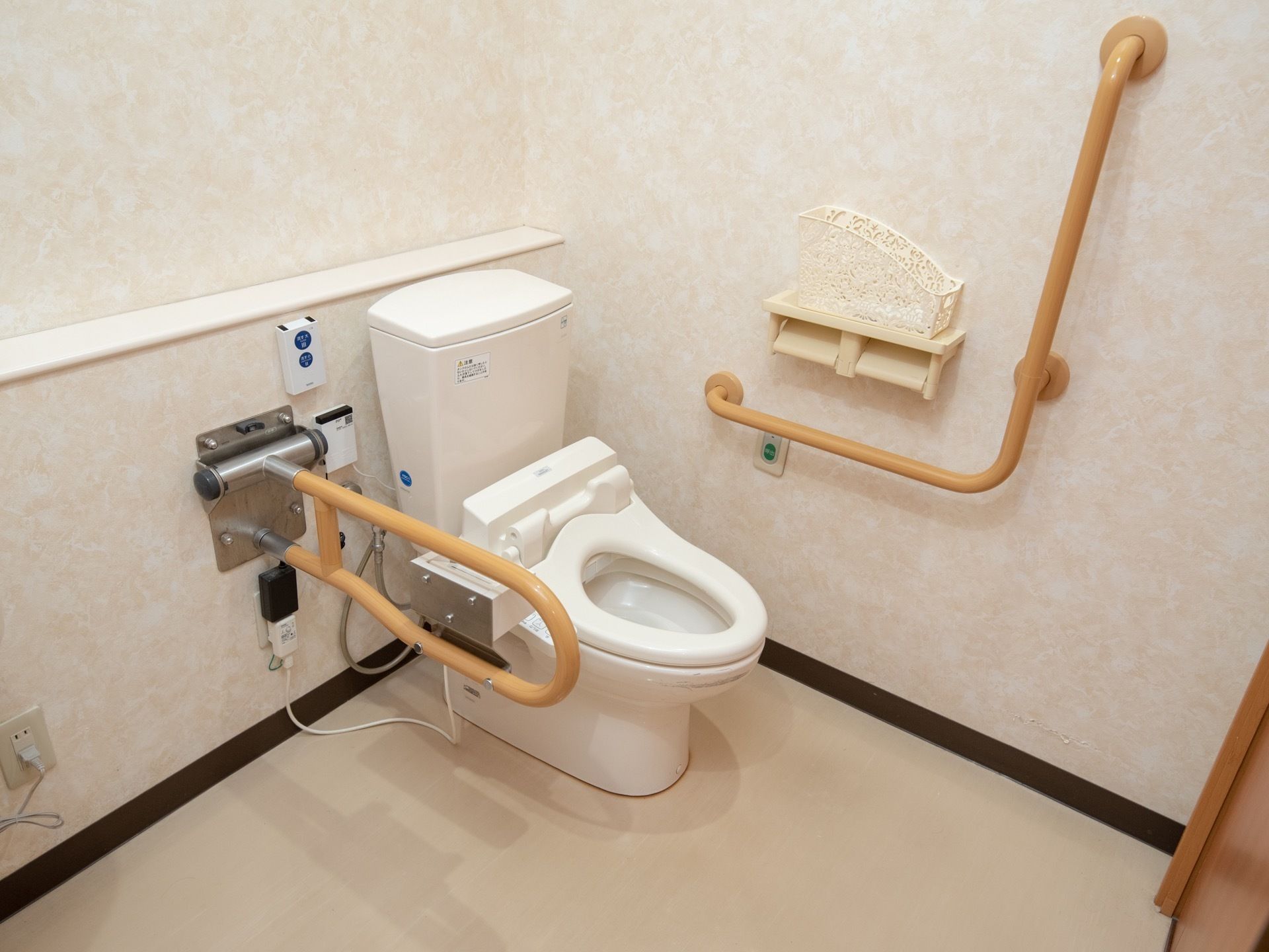 白を基調とした清潔感あふれる個室トイレ。壁には手すりやナースコール、ペーパーホルダーなどが設置されている。