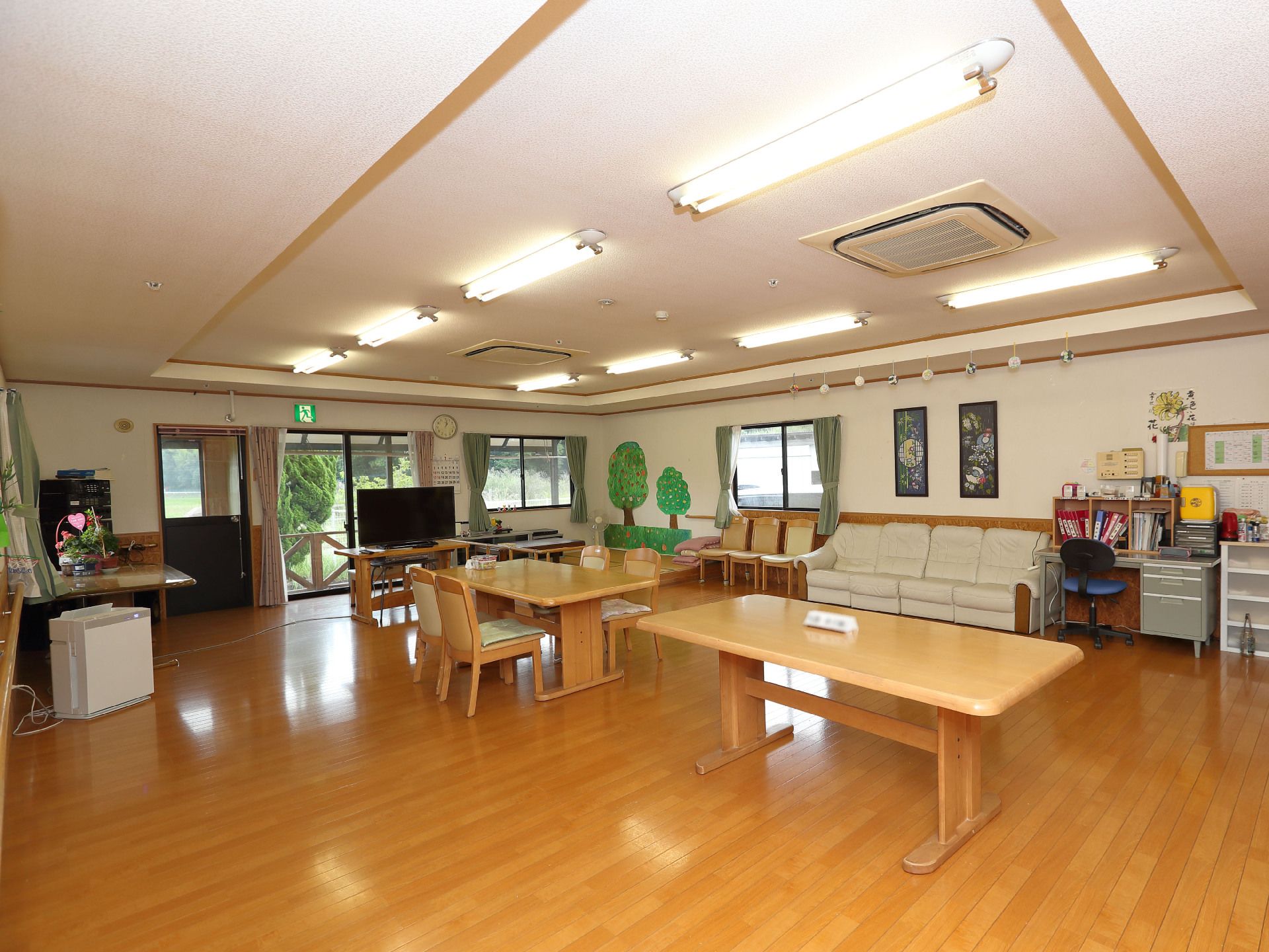 木製の長机が置かれた白い壁の広間