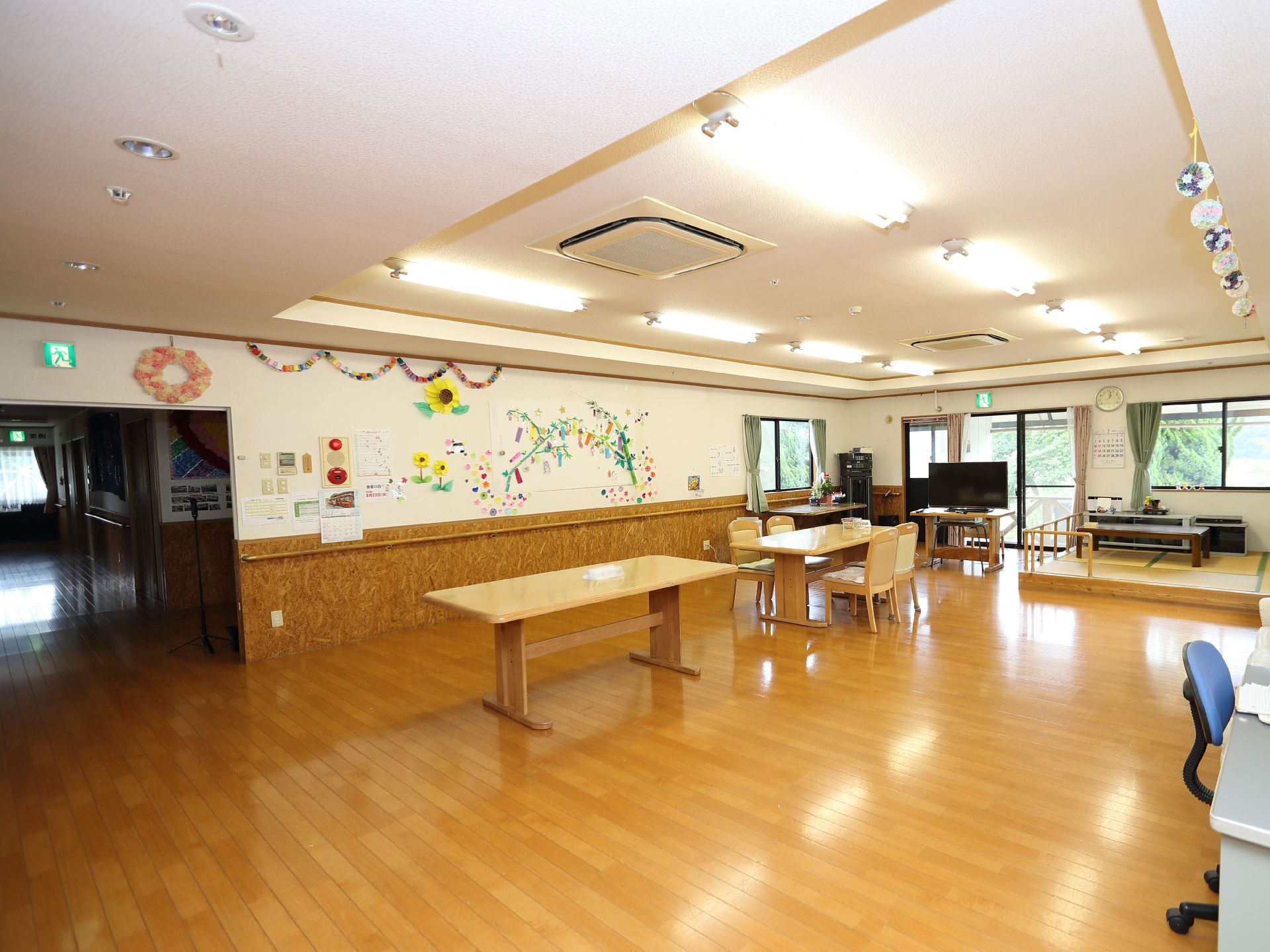 木製の長机が置かれた窓のある広間