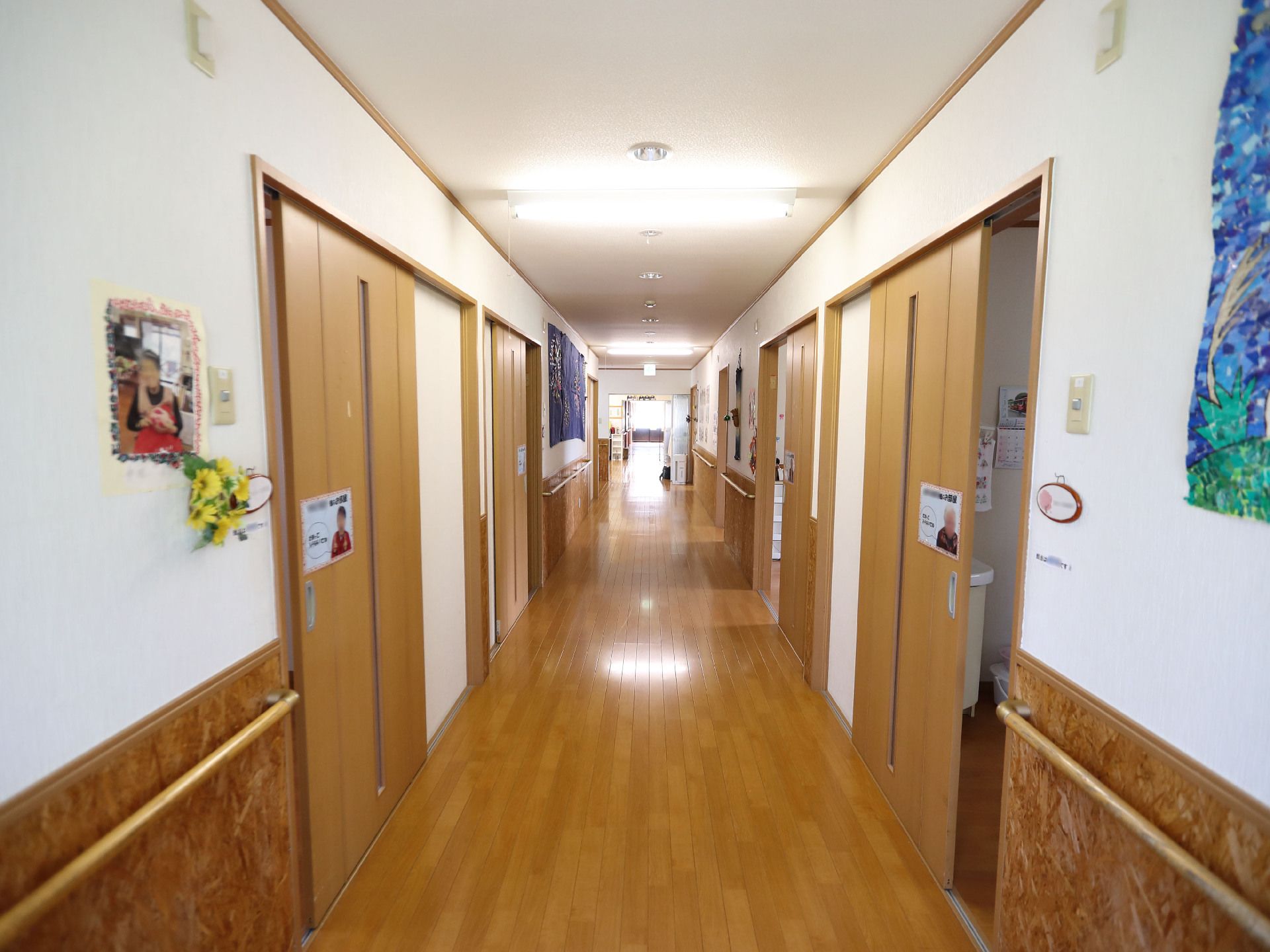 両側の白い壁に手すりが付いた直線に続いている廊下