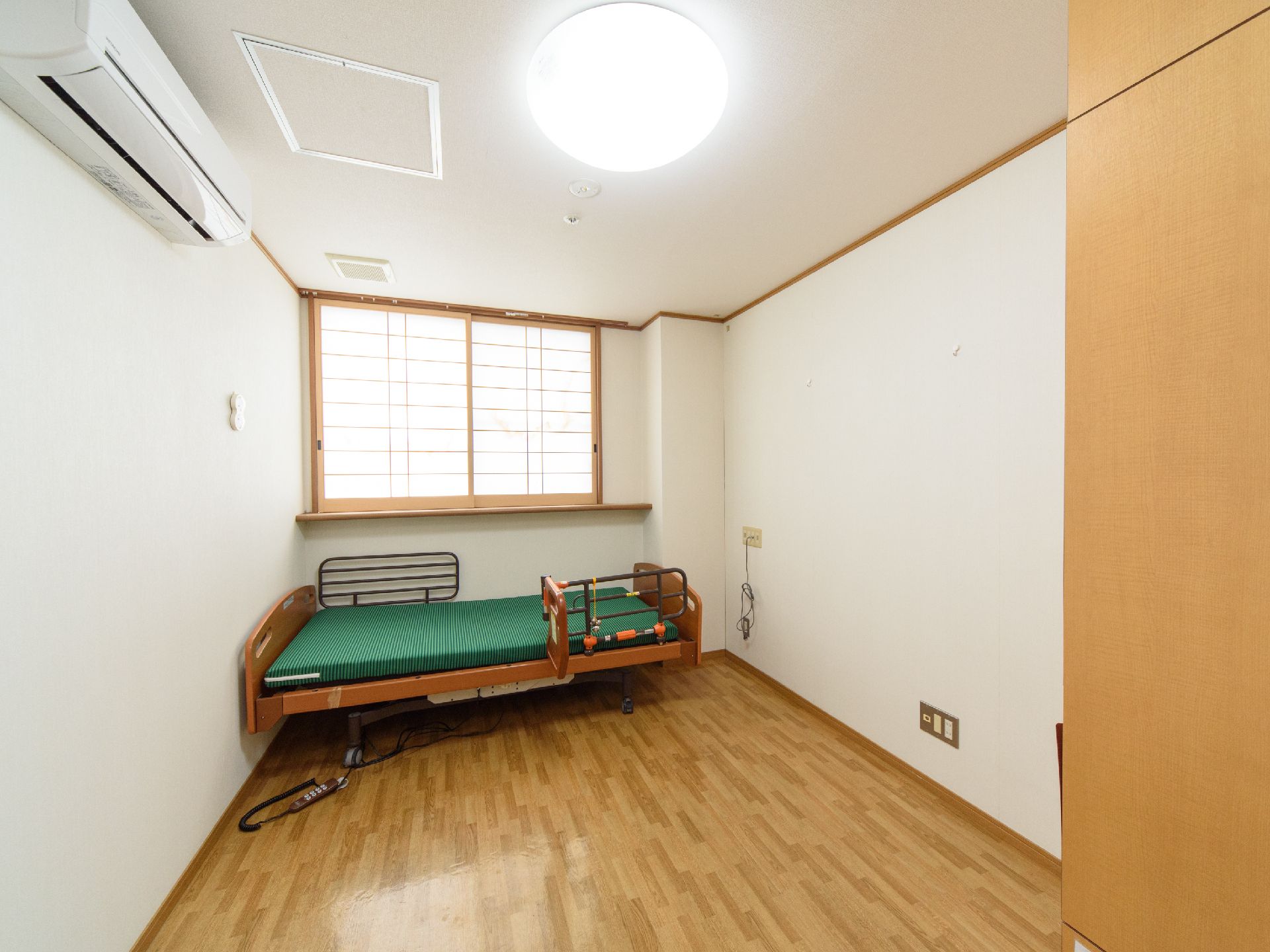窓に障子が取り付けられている電動ベッドが置かれている居室