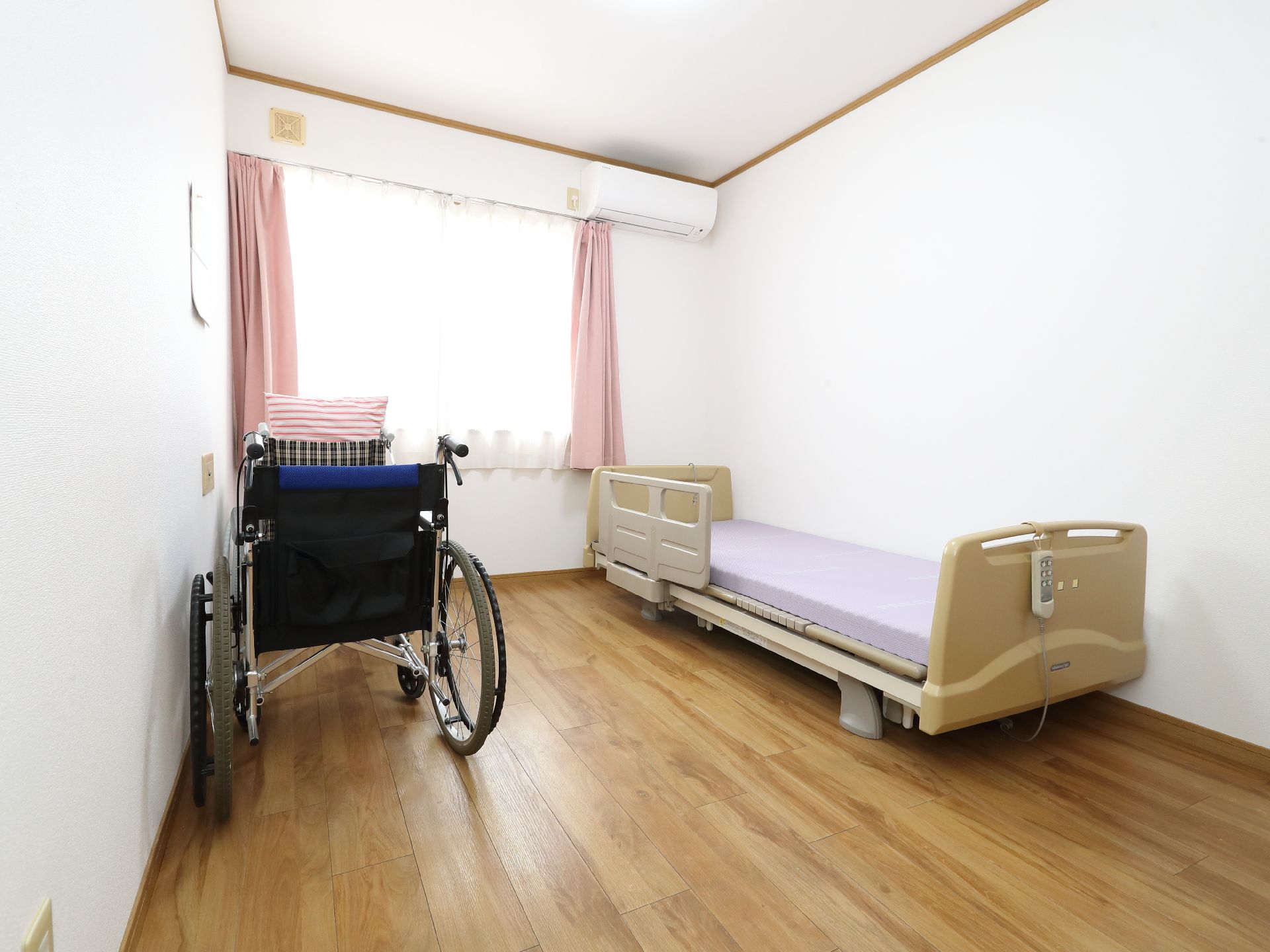 ベッドと車いすが置かれた白い壁の部屋