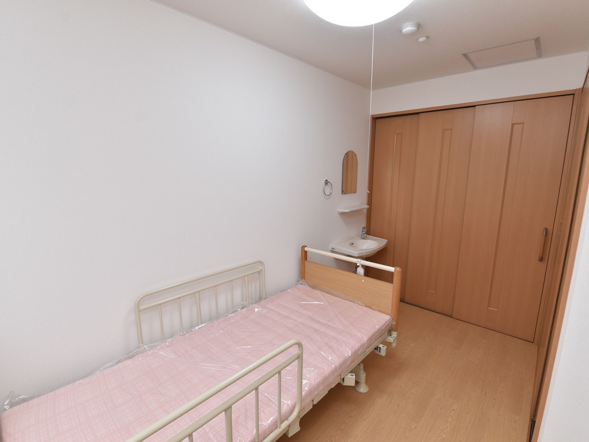 白い壁で清潔感のある居室になっている。電動式のベッドと、洗面台が設置された個室になっており、プライバシーを保つことができる。