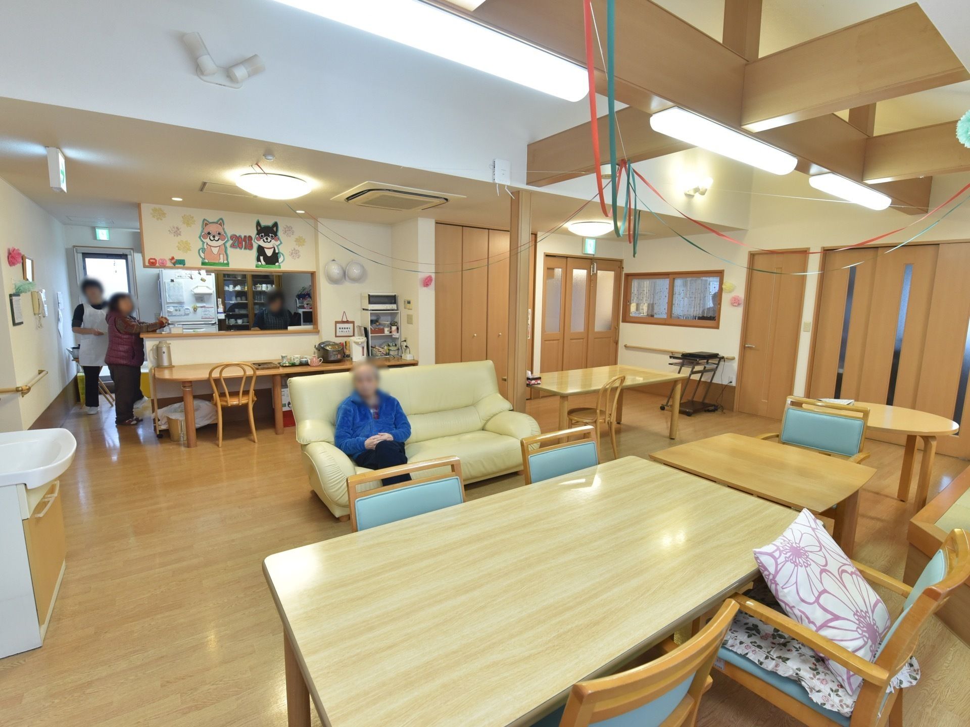 長テーブルには緑のいすが並べられている。木製の住宅に木製の家具が置かれ、温かみのある雰囲気。