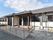 瓦屋根の日本家屋風の玄関がある。壁は白く扉と窓枠は黒の、ツートンカラーのデザインになっている。入り口にはスロープと手すりが設置されている。