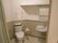 手すりが設置されたトイレには手洗い場もあり、ドアはではなくモスグリーンのカーテンを開け閉めするタイプ。
