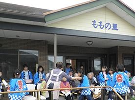 お祭りの様子を写した写真。ももの里の外観とその前に建つ人々