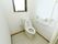 十分なスペースが確保されたトイレである。壁には、L型てすりや呼び出しボタンが設置されている。扉には、アコーデオンカーテンが採用されている。