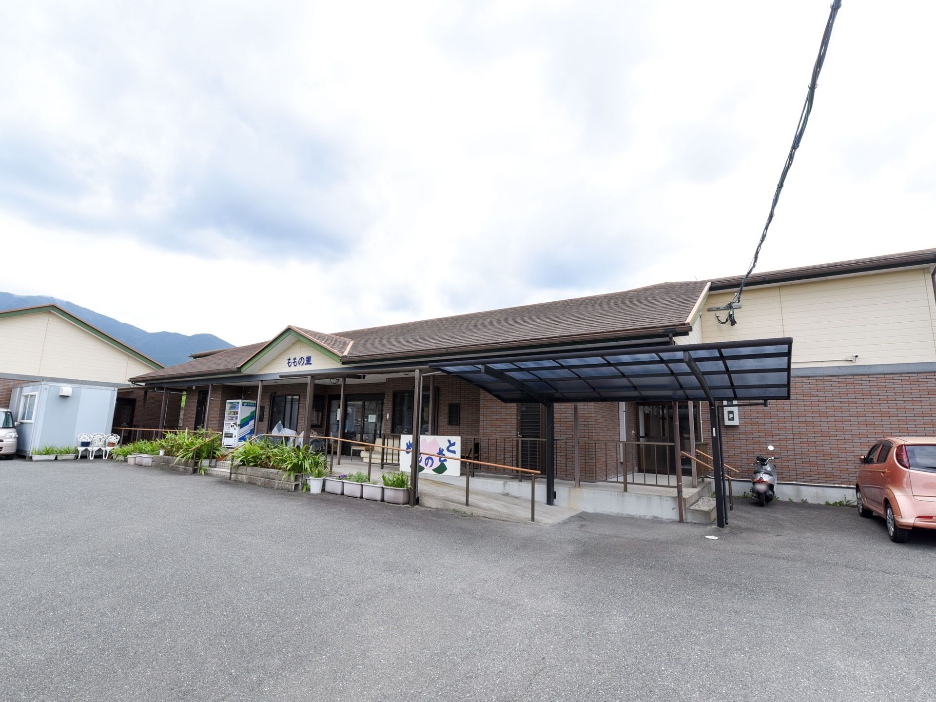 平屋建ての施設である。手すりが備わったスロープや階段がエントランスに設けられている。建物前は駐車スペースになっている。