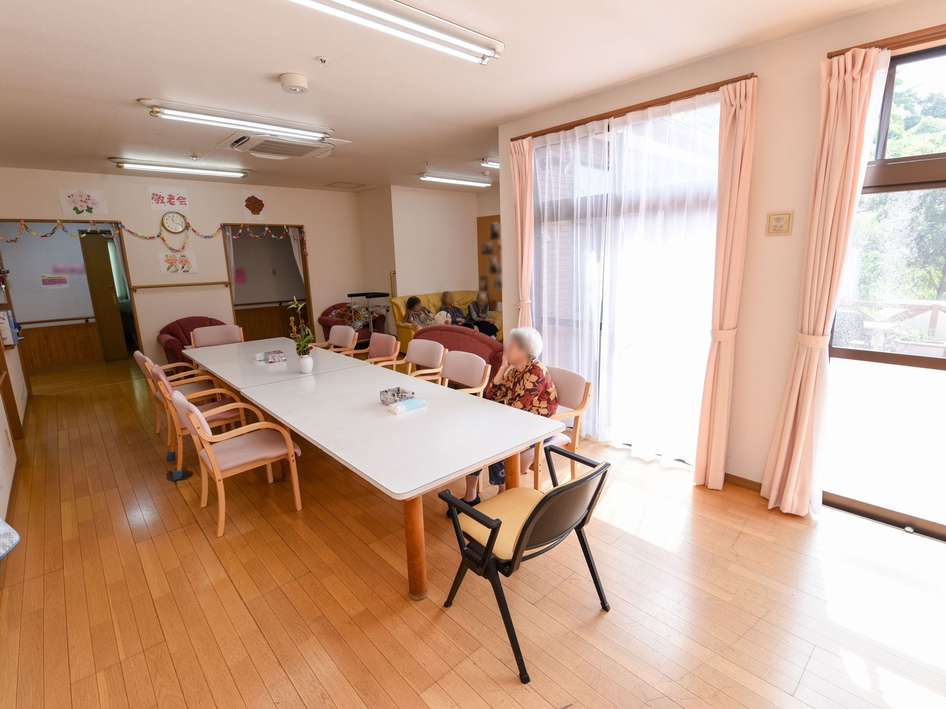 建物の中で話している看護師と医師、患者。明るい日差しが差し込んでいる様子