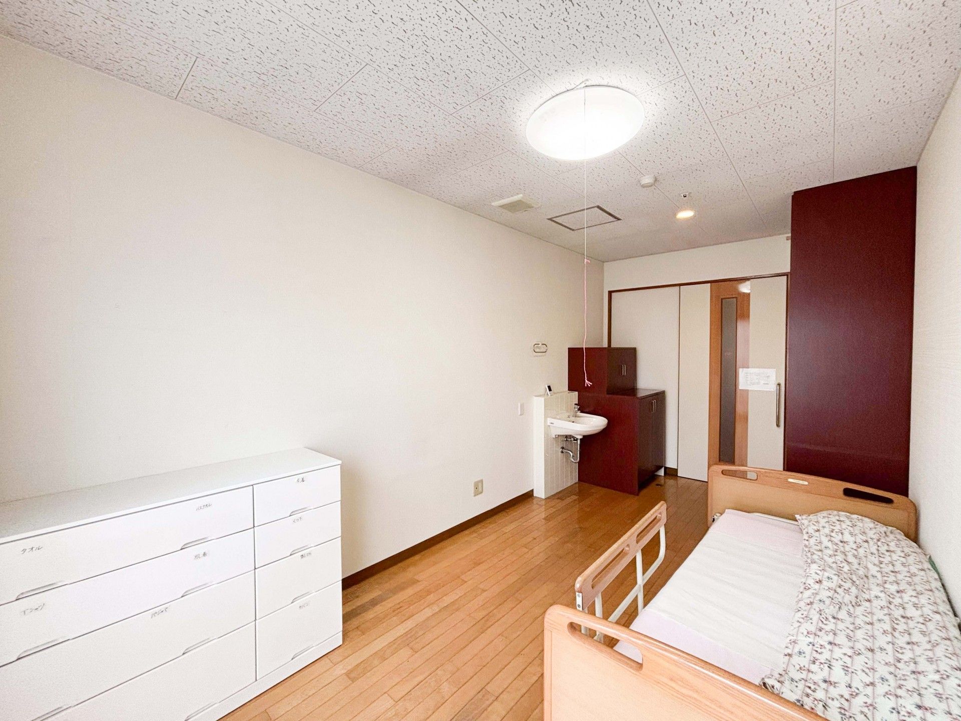 フローリングの共有スペースには木製のテーブルセットやソファが置かれ、車いす対応の洗面所が付いている。