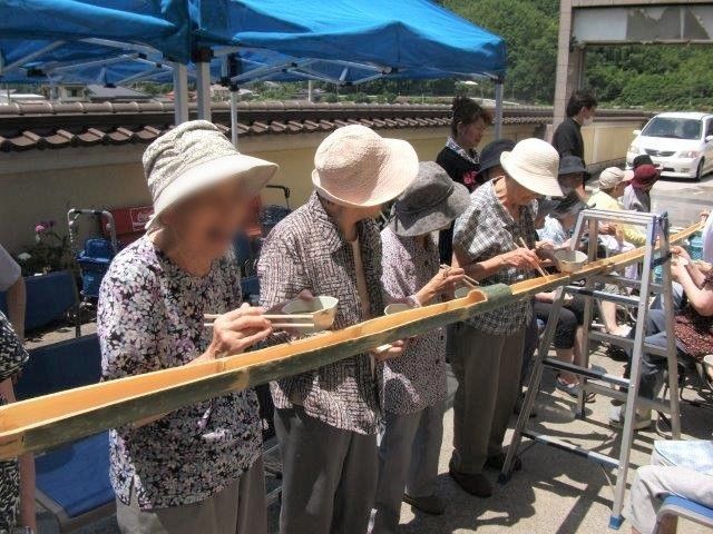流しそうめんに興じている高齢者とスタッフの様子。夏のイベントの写真