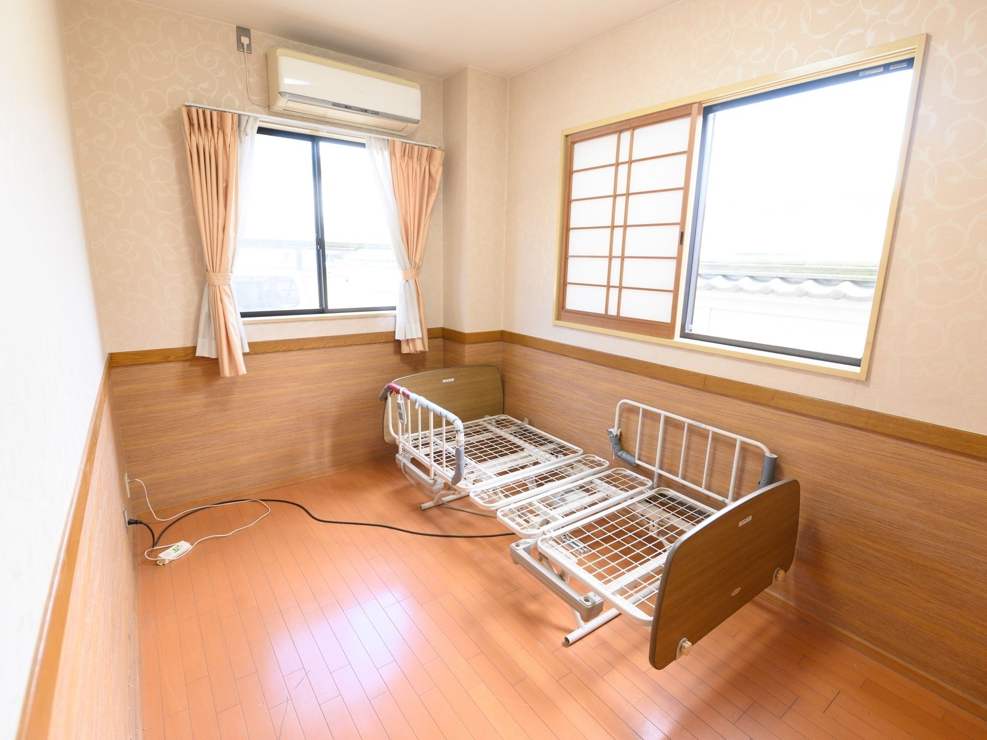 壁の1/3が木目で上の2/3はボタニカル模様の壁紙が貼ってある。カーテンの付いた窓と、障子の取り付けられた窓が付いている。