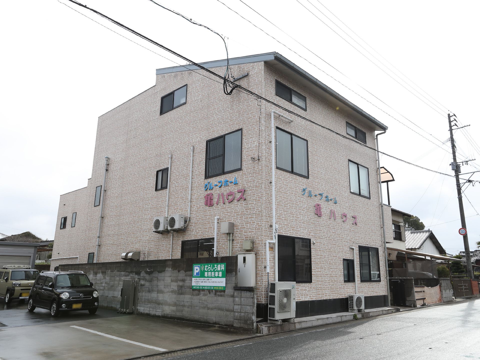 緑に囲まれ、落ち着きのあるモダンな色合いの老人ホームの外観