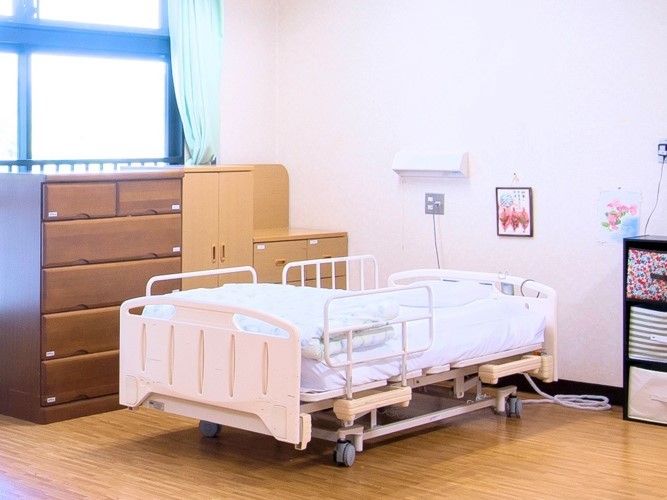 タンスが並んでいる窓辺とその近くにある介護用ベッドの様子。タンスが近くに置いてある
