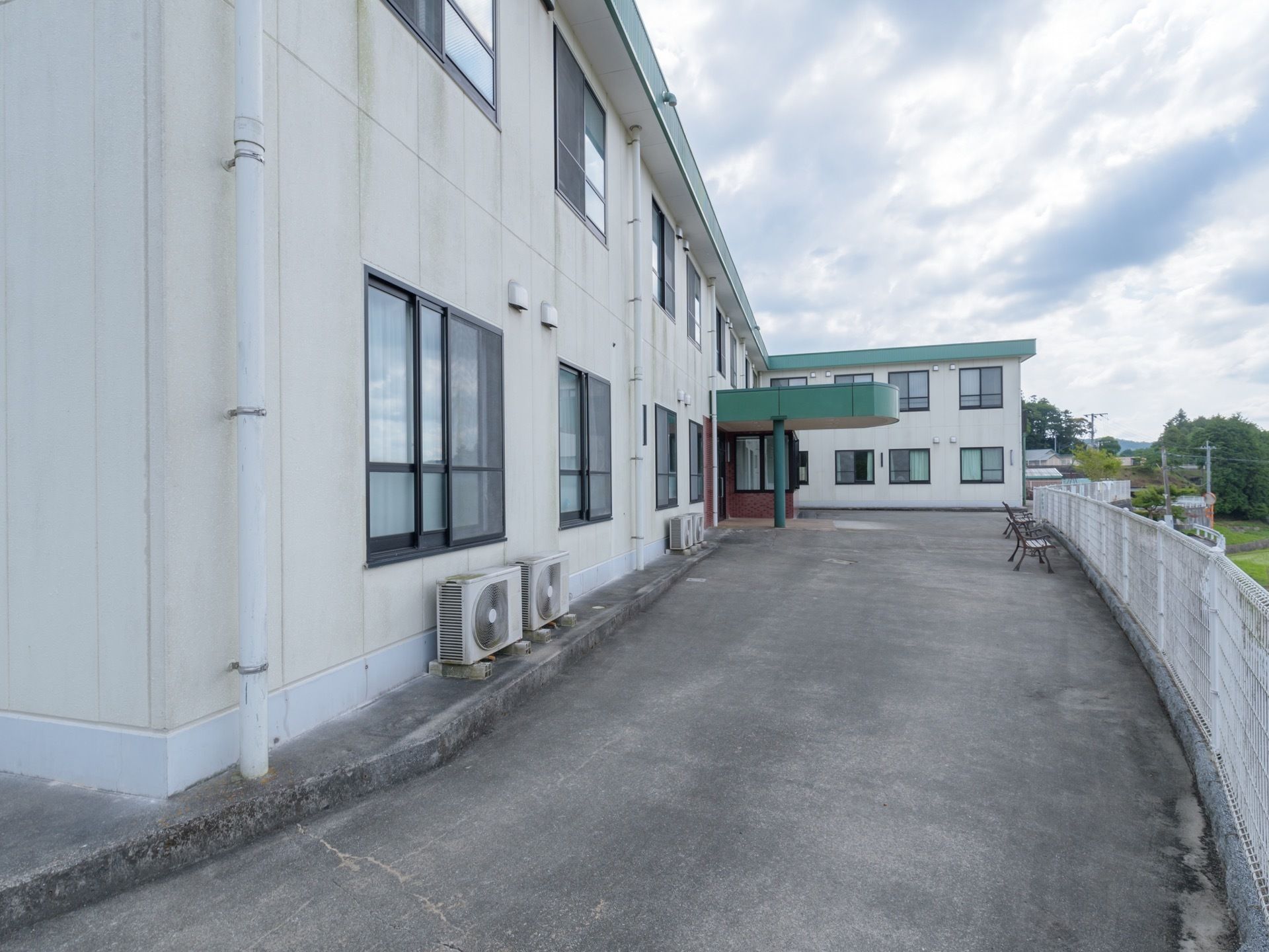 白色を基調とした外壁の２階建ての施設である。屋根や玄関前のひさしの部分は緑色に塗られている。敷地境界にはフェンスが設置されている。