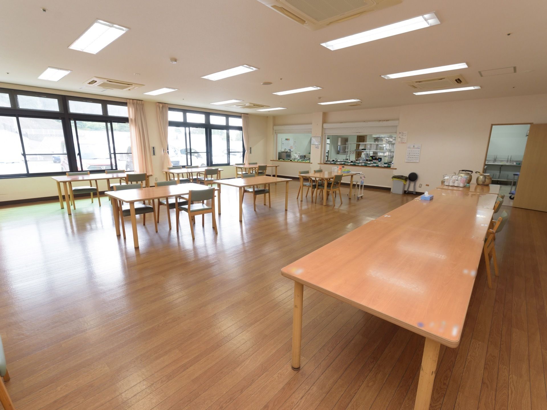 食堂の壁には窓がたくさんある。カウンター越しに調理場が見える。テーブルの上にやかんが２つ置かれている。