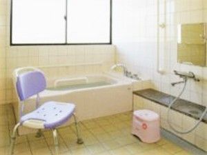 一人用の浴槽が設置された浴室。シャワーやシャワーチェアもあり、複数の手すりが壁についている。
