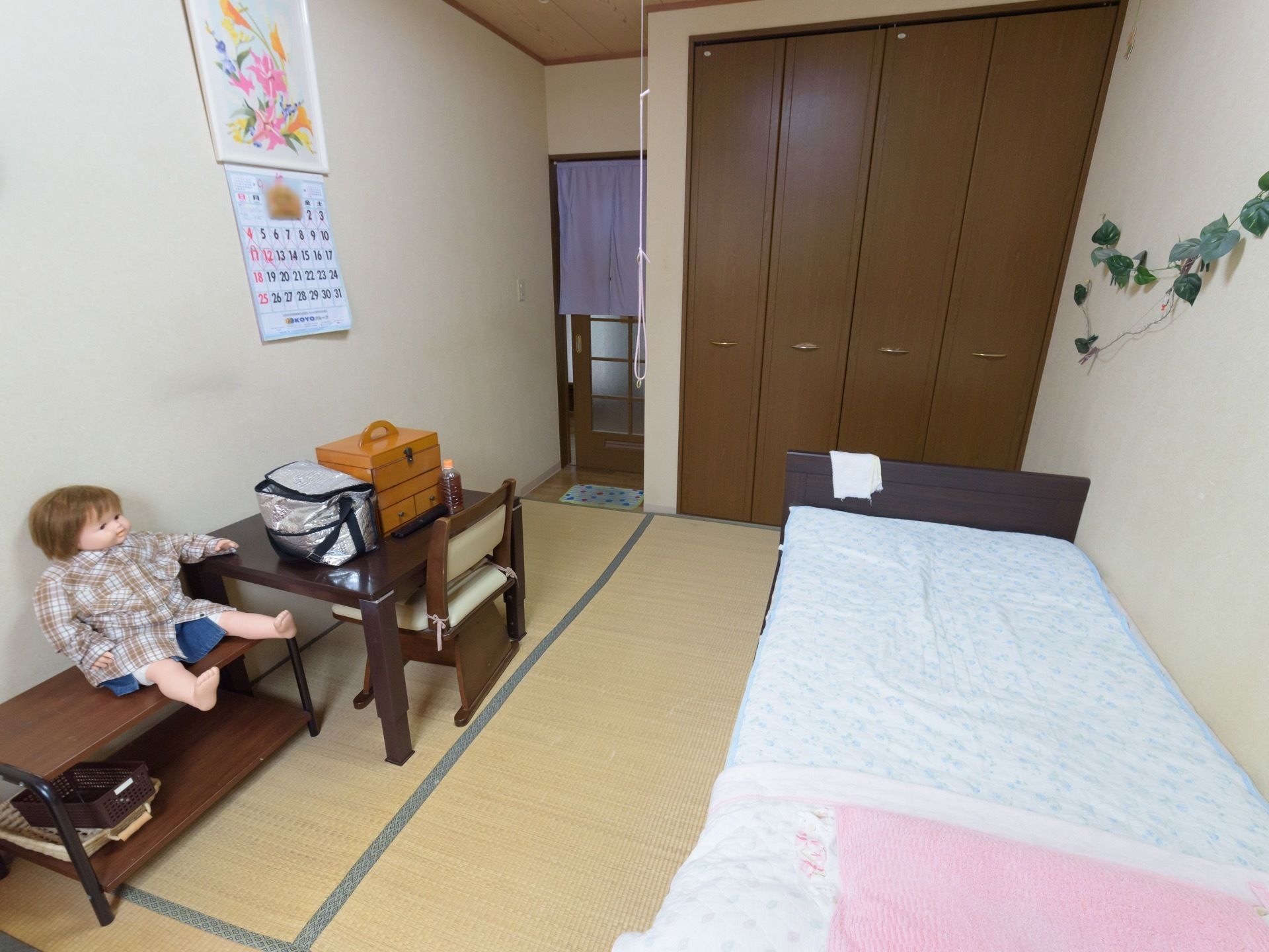 畳が敷かれた和室タイプの居室の一例である。右手に木製のベッドがあり布団が敷かれている。正面にはクロゼットがある。