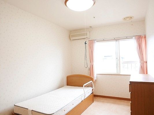 大きな窓が付いた明るい部屋には介護用ベッドやタンスが置かれ、寝具はついていない。