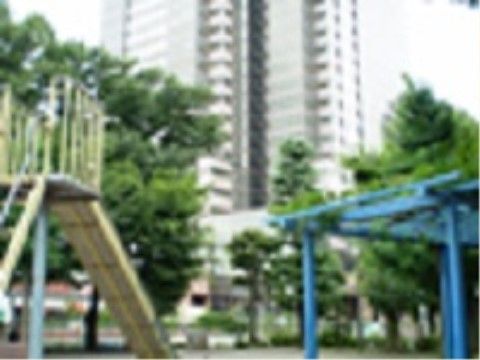 緑の多い公園が最寄り駅周辺にある。子供が遊ぶ遊具が設置されており、背後にタワーマンションが建っている。