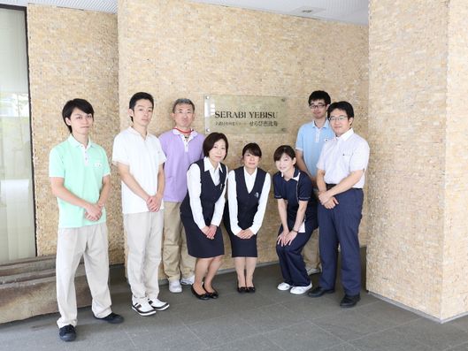 施設名のプレートとスタッフ