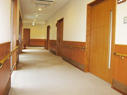 幅の広いグループホーム内の廊下の様子。両側に個室のドアと手すりがついている様子がわかる
