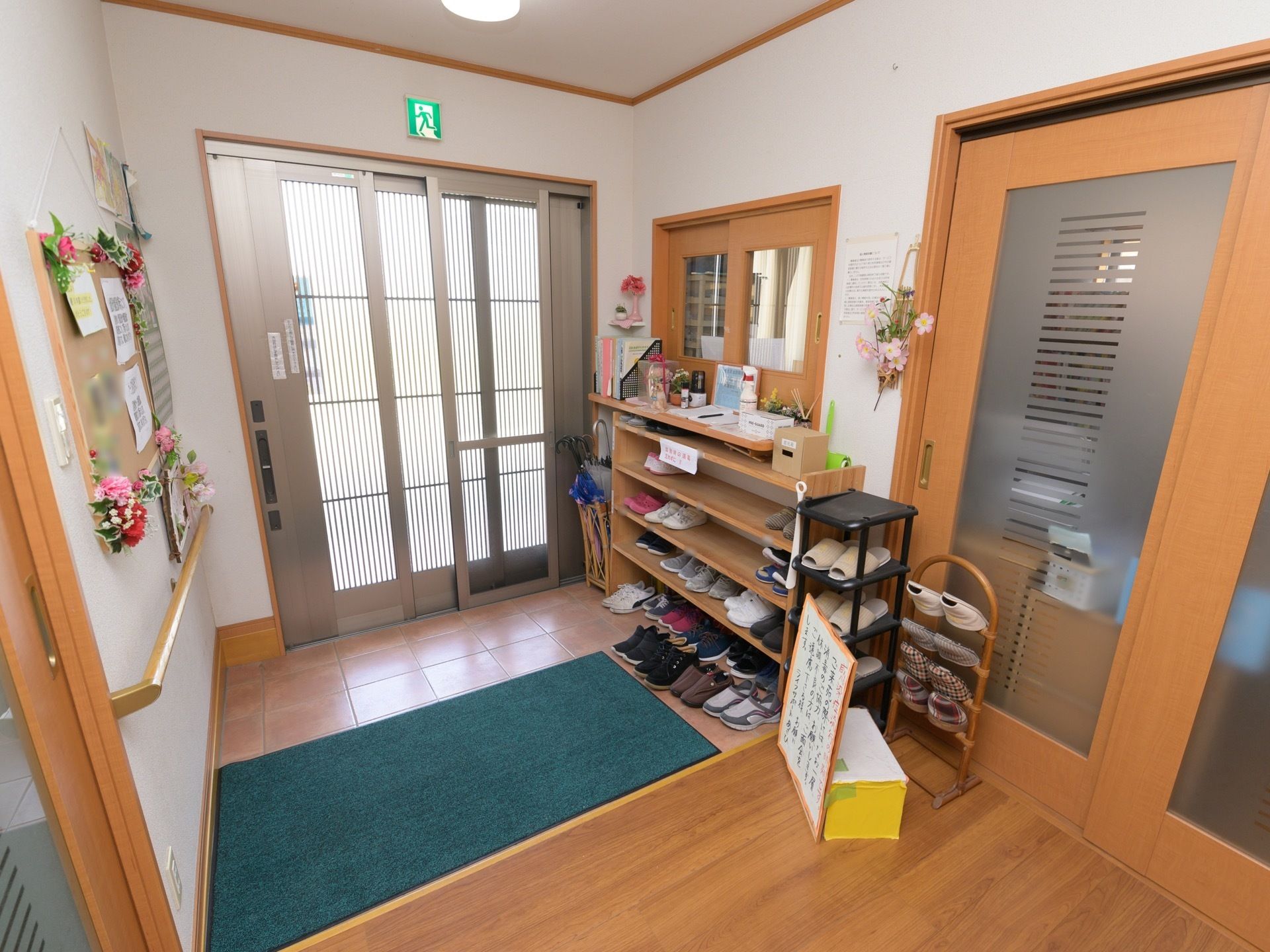 引き戸式の扉になっており、玄関にはマットが敷かれている。下駄箱には靴が収納されている。玄関から室内までは段差のないバリアフリー設計である。